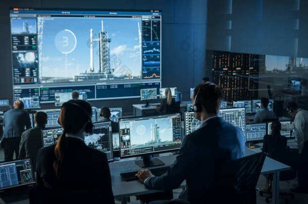 任务控制中心人员小组见证了成功的空间火箭发射。飞行管制员坐在电脑前展示及监察飞行任务。团队精神站起来鼓掌.