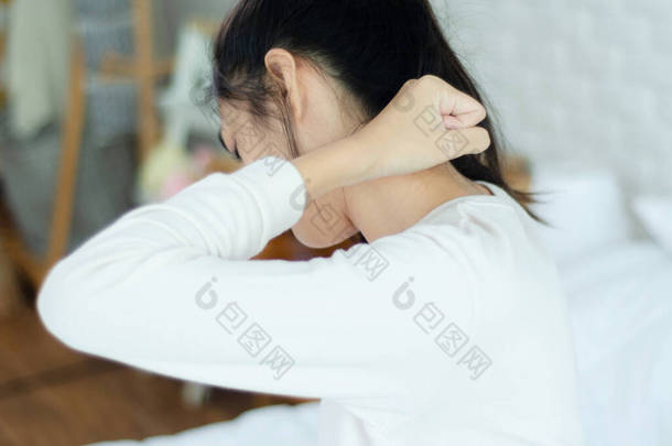 亚洲女人在卧室里穿着白色睡衣。2.她的脖子有点痛.