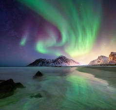 挪威洛福敦群岛上的北极光。山和海滩上方的绿色北极光。夜晚的天空与极光。夜冬天风景与极光。挪威的自然背景