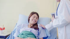 年轻的亚洲医生妇女在病床上为女病人说话和牵手。医学、年龄、保健、精神科医生和人的概念.