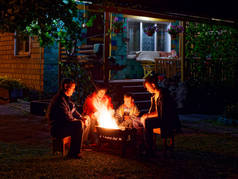 一群年轻的朋友深夜坐在炉边烤香肠