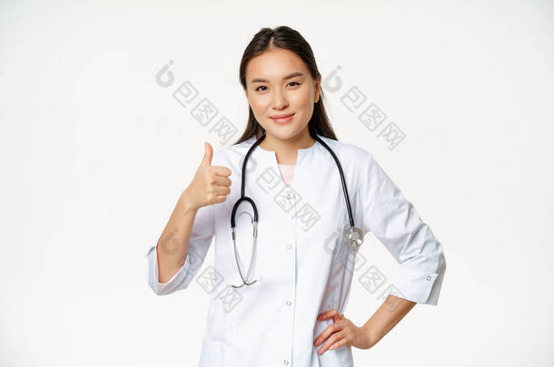 穿着医疗制服的专业医生微笑着露出大拇指.快乐的亚洲女医生<strong>证实</strong>了口臭，推荐产品，白色背景