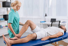 女性按摩师在门诊按摩台上对病人进行腿部按摩