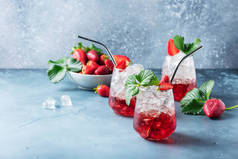 酒吧概念。红色鸡尾酒，冰和新鲜草莓蓝色背景。带有文本复制空间的选择性焦点图像
