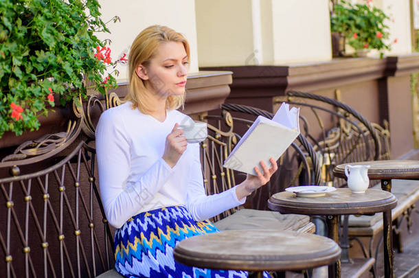 女孩在读畅销书时喝咖啡。读书是她的爱好。杯咖啡和有趣的书最佳<strong>组合完美</strong>的周末。妇女有饮料咖啡馆露台室外
