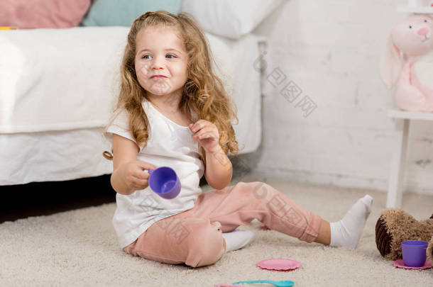 可爱的孩子玩塑料杯在地板上在儿童房