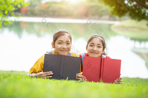 漂亮的亚洲双胞胎女孩或<strong>学生</strong>在公共公园<strong>看书</strong>。使用的<strong>教育</strong>概念