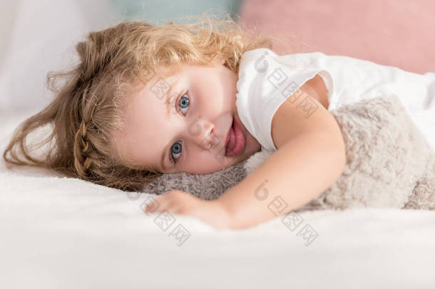鬼脸可爱的快乐的孩子躺在<strong>儿童房</strong>的床上看着相机