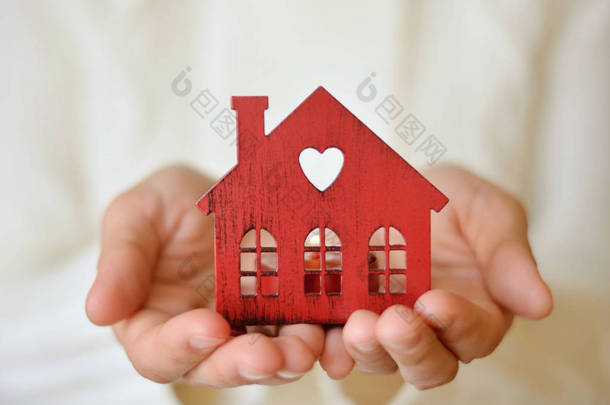 在女性手中的温暖和舒适的微型房子。关心和爱护.