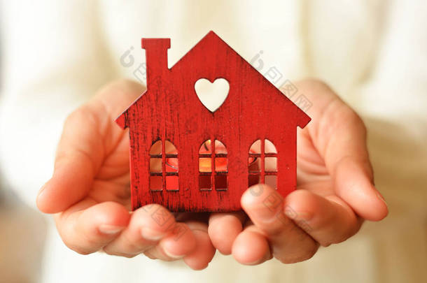 在女性手中的温暖和舒适的微型房子。关心和爱护.