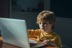 可爱的小学生玩和冲浪在线深夜。沉迷于网络游戏和社交媒体的孩子在笔记本电脑上无法入睡。儿童与网瘾的数字技术.