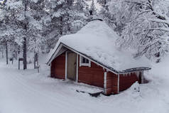 芬兰国家公园内雪地森林里的红色小屋
