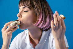 性感迷人的女人吃一块馅饼孤立在蓝色