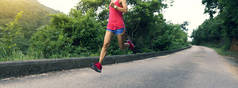 穿着运动服的女运动员在森林山路上奔跑。健身女孩在公园慢跑