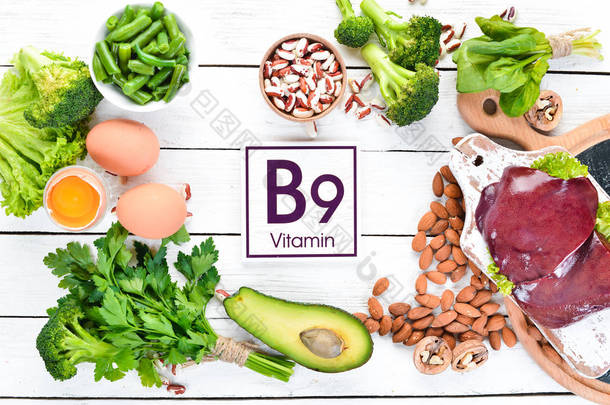 含有天然维生素B9的食物：肝脏、鳄梨、花椰菜、菠菜、欧芹、豆类、坚果，在白色木制背景上。顶部视图.
