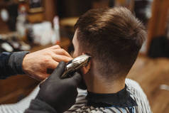 理发师拿着梳子剪客户的头发。专业理发店是一种时髦的职业.复古风格沙龙中的男性理发师和顾客