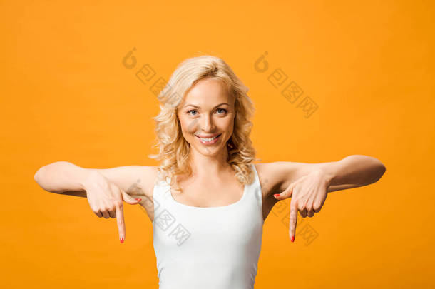 有吸引力的女人看着<strong>相机</strong>，并指着手指隔离在橙色