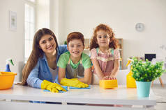 有妈妈和两个孩子在家里打扫卫生的快乐家庭。父母和孩子一起在室内做家务活