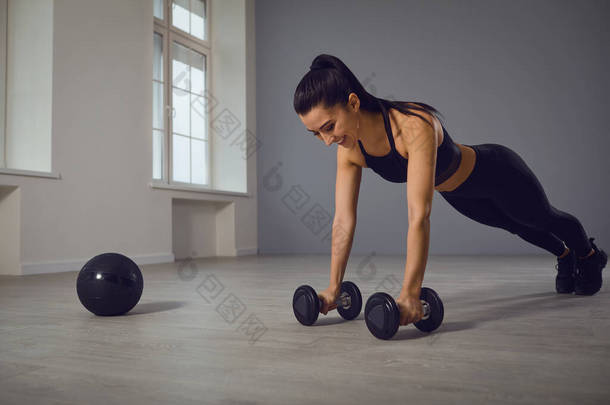 身穿黑色运动服的女运动员在室内做俯卧撑练习.