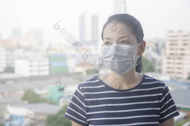 因城市空气污染而戴 n95 面罩的妇女有颗粒物, 或有城市建筑背景的 pm2。5
