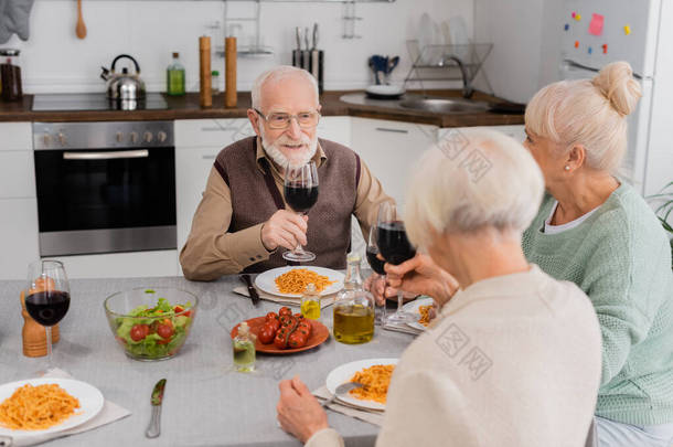 快乐的老人和退休的女人在餐桌边享用美味的午餐时<strong>轻声</strong>地喝着红酒