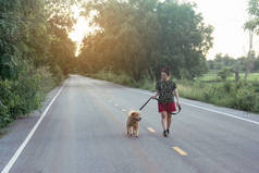 亚洲女人带着她的金毛猎犬走在公共道路上