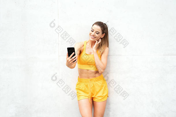 一个漂亮的运动健美女人在户外运动后用手机拍摄的照片.