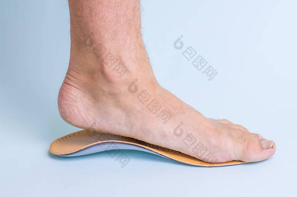 在矫形鞋垫旁边有脚部疾病迹象的成年男性的左腿。扁平足的治疗手段。脚疾病照片.