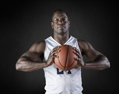 非洲裔美国篮球运动员肖像抱着一个球。黑色背景