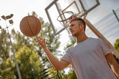 年轻街头篮球运动员手指旋转球