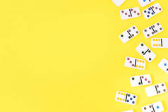 White dominoes lie randomly on the right on a yellow background with copy space on the left, flat la