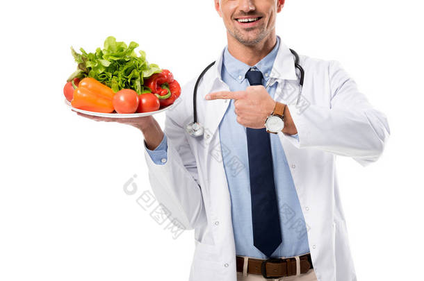 医生用手指指着盘子中的新鲜蔬菜的裁剪视图隔离白色, 健康饮食的概念