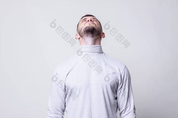 人向上看。猪鬃男装白色领毛衣衬衫抬头看着他的头上灰色背景复制空间