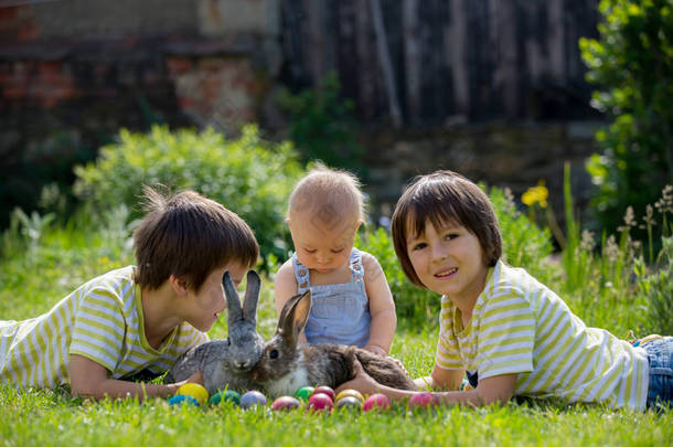 可爱的孩子, 男孩兄弟, 幼儿和学前班, 玩小兔子和复活节彩蛋在一个盛开的花园, 春天。男孩玩兔子, 蛋狩猎为假日