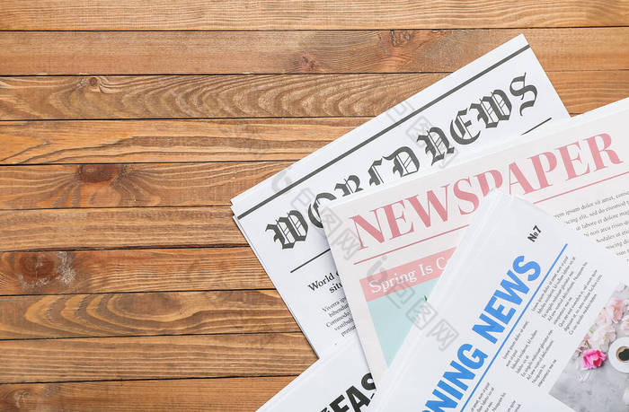 Newspapers on wooden background, closeup