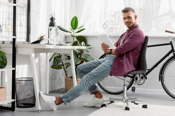 放松的人坐在椅子上与数字平板电脑在家里的办公室