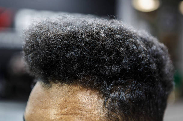 <strong>理发店</strong>里的年轻黑人 Unshorn 头发。关闭在<strong>理发店</strong>沙龙的无胡子的非洲家伙卷曲的锁。男性美容治疗理念