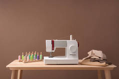 现代缝纫机, 一组线和织物在桌子上的颜色背景