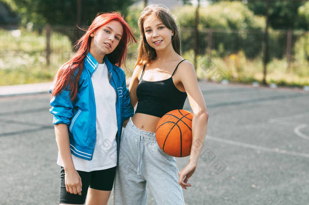 两个在运动场上打篮球的迷人女孩的画像。友谊，最好的朋友，运动