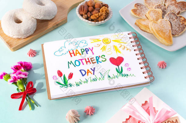 母亲日早餐卡片是由一个孩子做的.祝您<strong>母亲<strong>节</strong></strong>快乐。在一个彩色的背景。煎饼的形式有心脏、甜甜圈、坚果、康乃馨、礼物和一张明信片，由孩子们为<strong>妈妈</strong>做.