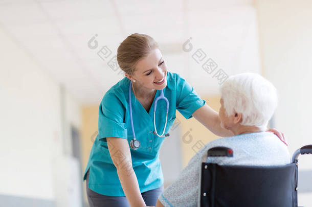 坐在<strong>轮椅</strong>上的<strong>老年</strong>妇女，医院内有护士