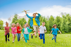 跳跃的男孩抱着大飞机玩具及儿童