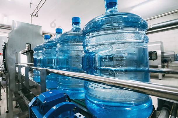 自动输送<strong>机</strong>生产线上装有净化饮用水的蓝色塑料瓶。 供水厂