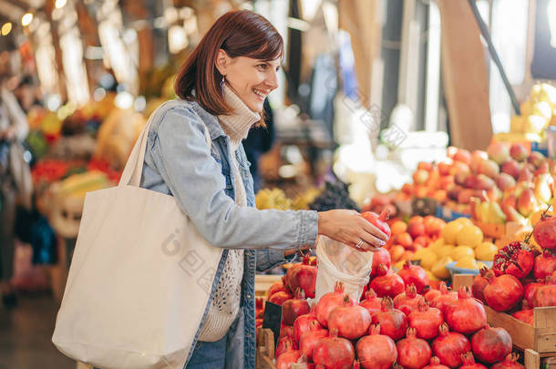 年轻妇女把水果和蔬菜放在棉花生产袋里，放在食品市场。可重复使用的<strong>环保袋</strong>购物。可持续的生活方式。生态友好理念.