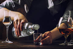 酒保在旧酒吧柜台上用小杯倒伏特加或龙舌兰酒。复古木背景在酒吧或酒吧, 晚上的心情。文本、调理、选择性对焦的位置