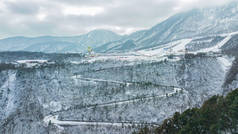 空中无人俯瞰西岭雪山,四川滑雪场紧邻成都.山路蜿蜒穿过树林、滑雪场和旅游基地。冬季体育活动.