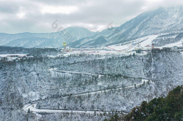 空中无人俯瞰西岭雪山,四川滑雪场紧邻成都.山路蜿蜒穿过<strong>树林</strong>、滑雪场和旅<strong>游</strong>基地。冬季体育活动.