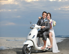 新婚夫妇在海滩上骑白色摩托车