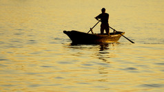 在日落时分的大海背景上跟一个男人小船