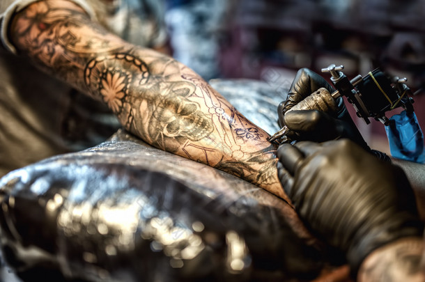 纹身艺术家绘画在胳膊上和客户端的皮肤上